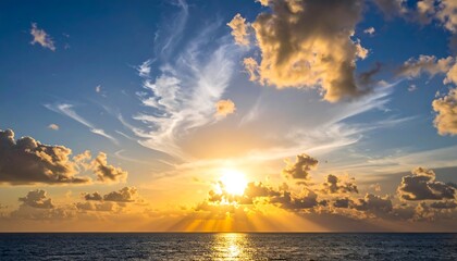 Bright sunburst over the ocean water, with textured clouds spanning the clear blue horizon