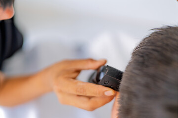 Barber giving haircut to customer with electric clipper
