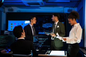 Automotive engineer presenting electric car design on large digital screen. Technical team analyzing vehicle aerodynamics and engine performance data in high-tech laboratory.