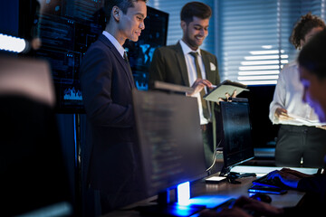 Automotive executives discussing electric car market strategy. Business leadership team analyzing vehicle sales data and future design trends in modern night office.