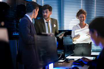 Automotive executives discussing electric car market strategy. Business leadership team analyzing vehicle sales data and future design trends in modern night office.