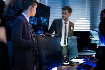 Industrial design team planning smart mobility transport. Professionals analyzing futuristic car prototype and engineering schematics on digital screens at night.