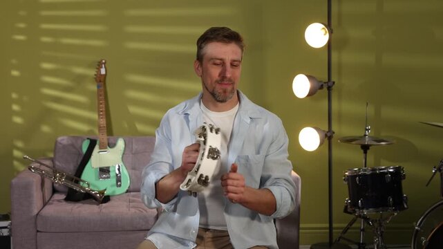 Man playing tambourine at home. Musical instrument