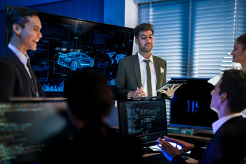 Fototapeta premium Industrial design team planning smart mobility transport. Professionals analyzing futuristic car prototype and engineering schematics on digital screens at night.