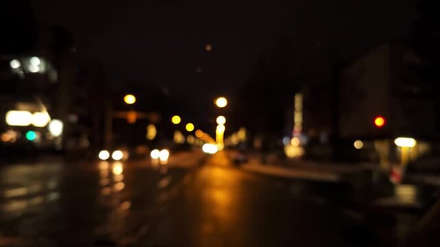 Driving through snowy urban road at night from inside the car, light bokeh and motion blur