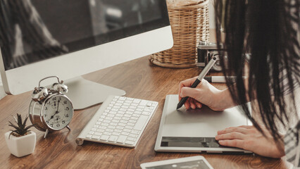 Young female designer using graphics tablet while working with computer
