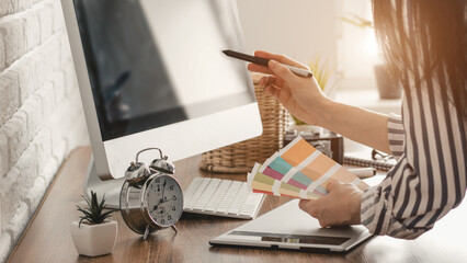 Young female designer using graphics tablet while working with computer