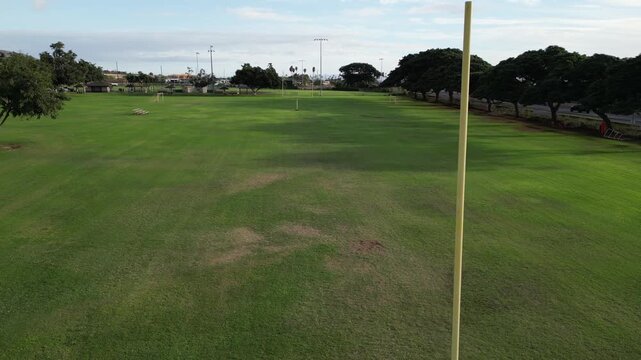 flying over football field with yellow uprights (american touchdown) rural tropical public park in lahaina hawaii (goal scoring green grass) empty nobody team sports game fun athletics high school sky