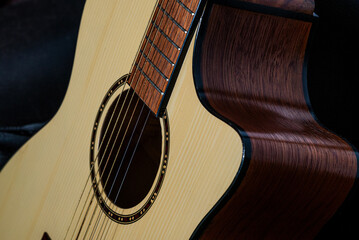 Close-up detail of an acoustic guitar body with wooden texture and strings, captured in low light...