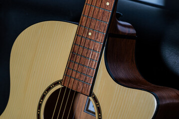 Close-up detail of an acoustic guitar body with wooden texture and strings, captured in low light...