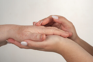 Fototapeta premium Young woman holding grandmothers hand. Care concept. Close up young hand holding an old hands. Elderly woman hands close up. Hand help bridges age. Hand help connects old young.