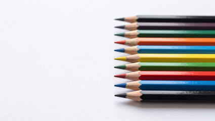 Fototapeta premium A neat row of sharpened colored pencils displaying a vibrant spectrum of colors is arranged against a clean white background, creating a minimalist and artistic composition.