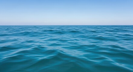 Obraz premium A vast expanse of calm, blue ocean with gentle waves and a clear, blue sky in the background.