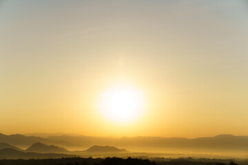 Naklejka premium Golden sunrise over the layered mountain during foggy day.