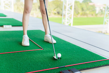 Close up of golfer preparing to hit golf ball on turf at driving range