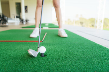 Close up of golfer preparing to hit golf ball on turf at driving range