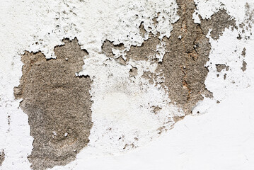 White paint peels from weathered wall, revealing coarse gray surface beneath. Contrast in textures and tones evokes age, decay, and the raw beauty of material deterioration