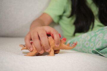 Child plays with dinosaur toy on a couch in living room © Towfiqu Barbhuiya 