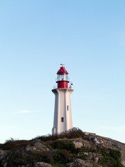 Lighthouse in rocky beach with clear skies