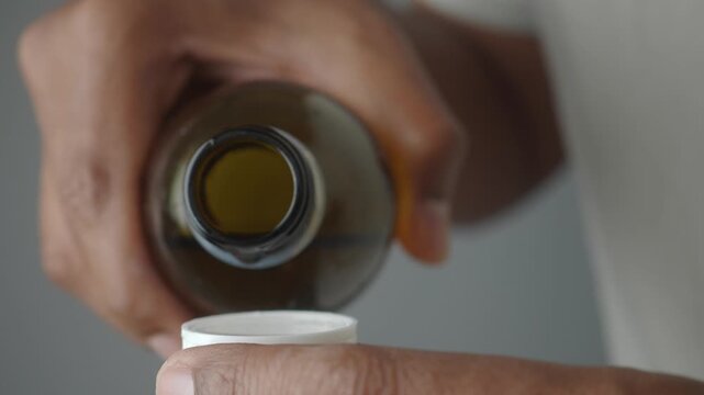 Pouring liquid medicine into a dosage cup
