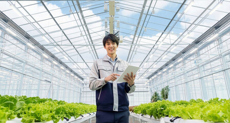 植物工場でタブレットを操作する若い男性作業員（スマート農業）