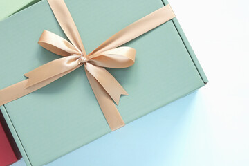 Top view of an elegant sage green gift box tied with a gold satin ribbon for mockup on blue background. Luxury present concept for birthday, wedding, or anniversary, and valentine's day.