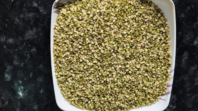 Split green gram (Moong Dal) in a white ceramic bowl on a dark marble background
