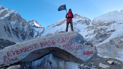 Triumphant mountaineer celebrates a monumental achievement at Everest Base Camp, proudly displaying a national flag against the breathtaking backdrop of the Himalayan peaks, marking a significant mile