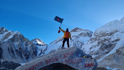 Jubilant climber celebrates successful ascent, proudly waving national flag at high-altitude base...