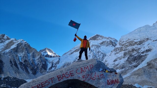 Jubilant climber celebrates successful ascent, proudly waving national flag at high-altitude base camp, surrounded by stunning grandeur of snow-capped mountains - Powered by Adobe