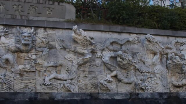 3D stone relief of Asian dragon scene on ornate stone wall, pan shot