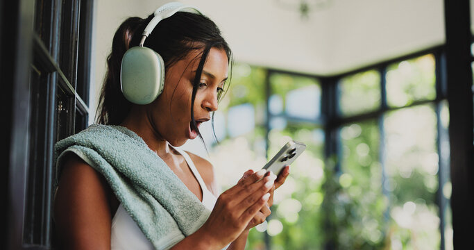 Shocked, athlete and woman with smartphone, house and listening to video on social media and online. Fitness, entertainment and surprised by weight loss trend on web, mobile or person with headphones - Powered by Adobe