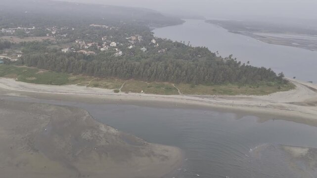 Aerial evening view of Morjim turtle nesting beach in Goa during winter, showing gentle ocean waves, coconut palms and coastal vegetation, with Chapora River and soft mist creating a calm scene