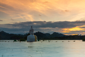 Golden Sunset of Submerged Buddha Statue in water (Phra Chom Nam) in Khao Rakham Reservoir at Trat Province of Thailand