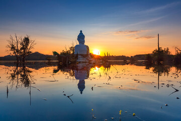 Majestic Buddha Statue Reflected in Water at Sunset (Phra Chom Nam) in Khao Rakham Reservoir at Trat Province of Thailand
