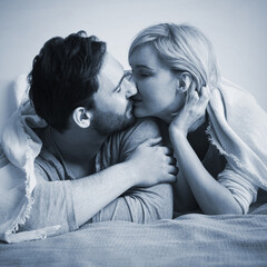 Blue cool tone monochrome bw image - inlove kissing couple with closed eyes lay on bed. Blond woman, brunette bearded man at home. Love, relationship, happy family, dating. Square