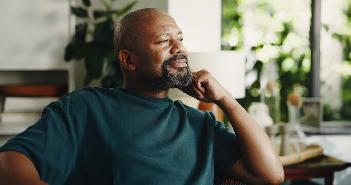 Relax, smile and reflection with mature black man in home for nostalgia, vision or positive mindset. Thinking, daydreaming and happy person with peace, calm and thoughts in living room on weekend