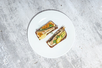 Open-faced sandwiches with sardines and pickles on white plate