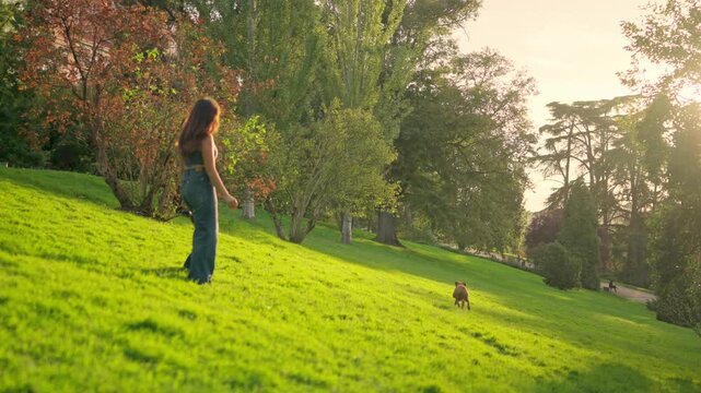 Woman playing fetch with her dog in a sunny park