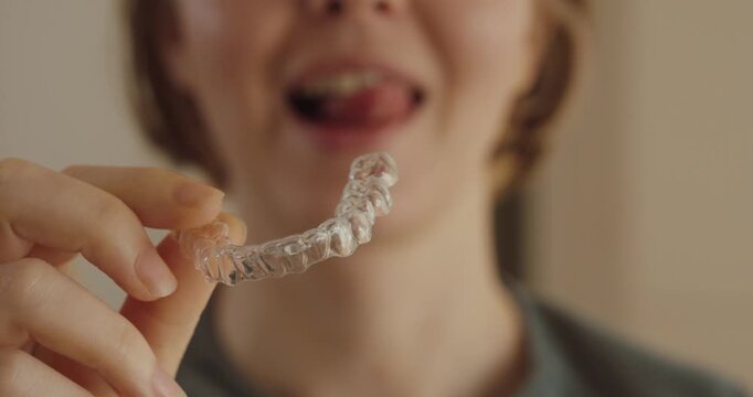 Close-up of a woman holding a transparent dental aligner &mdash; modern orthodontic care and clean lifestyle concept.