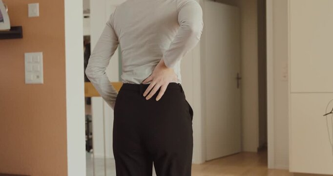A woman touching her lower back in pain at home &mdash; concept of backache, muscle tension, and everyday discomfort.