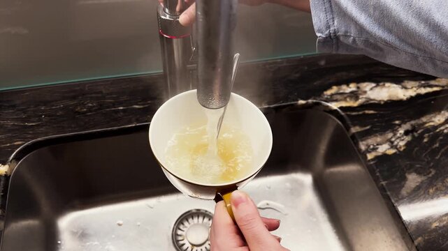Close-up of a person pouring hot water into a cup to make tea &mdash; cozy home moment and daily kitchen routine.