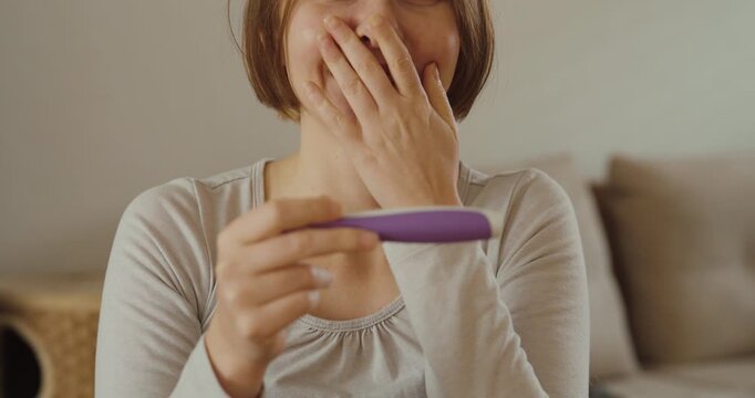A joyful woman smiling and celebrating after seeing a positive result on a pregnancy test &mdash; concept of happiness, new beginnings, and family planning.