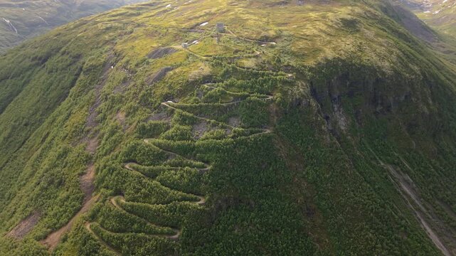 A Steep, Winding Mountain Road Climbs Through Lush Slopes at Tusenmeteren, &Oslash;vre &Aring;rdal, Norway - Aerial Drone Shot
