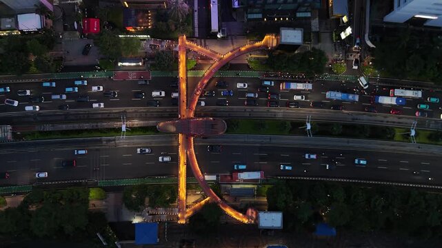 Jakarta, Indonesia, December 19, 2025: Aerial drone view of Jakarta cityscape above Jalan Jenderal Sudirman at the iconic Pinisi Pedestrian Bridge (JPO Pinisi)