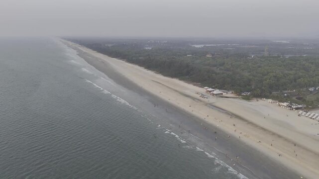 Aerial view of Mobor Beach, South Goa, showing a long stretch of white sandy coastline with gentle ocean waves and lush Goan coastal vegetation during the winter season.