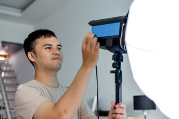 Young Man Adjusting Lighting Equipment in Modern Studio Setting