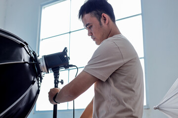 Photographer Adjusting Studio Lighting Equipment in Modern Studio