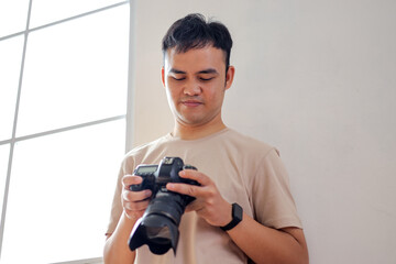 Young Photographer Reviewing Photos on Camera in Bright Room