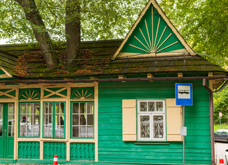 Traditional wooden bus stop building painted green with ornate trim and a clear bus sign. Vintage...